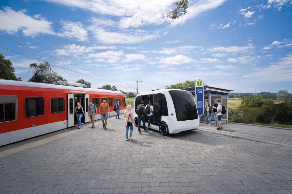 Luftaufnahme einer Gleisbaustelle im herbstlichen Wald: Ein grüner Schienenkran hebt ein großes, gewölbtes Betonelement vor ein Tunnelportal der Hermann-Hesse-Bahn, um eine Einhausung für den Fledermausschutz zu errichten