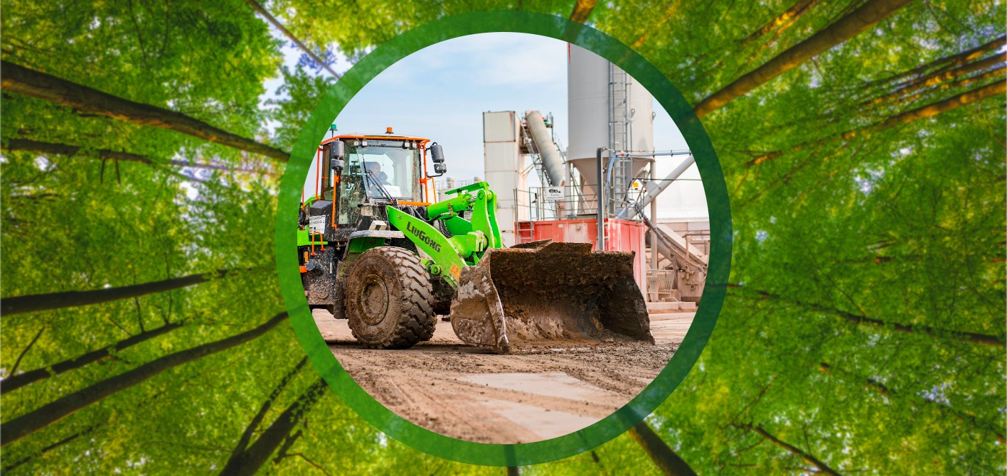 CO2-Reduktion in Bauprojekten: Nachhaltige Baumaschinen im Einsatz Ein grüner Radlader steht auf einer Baustelle vor industriellen Silos. Die Szene, umrahmt von tiefgrünen Bäumen, hebt den Einsatz nachhaltiger Technologie und die Reduktion von Emissionen im Bausektor hervor.