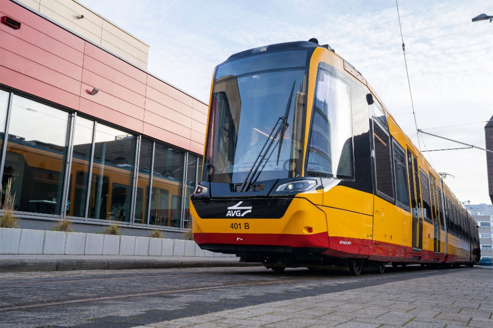 Luftaufnahme einer Gleisbaustelle im herbstlichen Wald: Ein grüner Schienenkran hebt ein großes, gewölbtes Betonelement vor ein Tunnelportal der Hermann-Hesse-Bahn, um eine Einhausung für den Fledermausschutz zu errichten